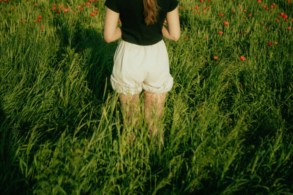A person stands in tall green grass.